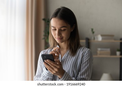 Thoughtful Teen Female Looking On Phone Screen Read Pleasant Message From Beloved Person With Light Smile Ponder On Text Of Answer. Interested Young Lady Check Mail Client On Cell Wait For Good News