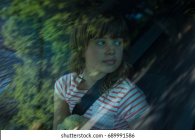 Thoughtful teenage girl with teddy bear sitting in the back seat of car - Powered by Shutterstock