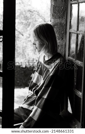 thoughtful teenager girl sitting on the windowsill near the open window, b-w Stock fotó © 