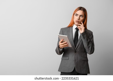 Thoughtful transgender secretary with tablet computer on grey background