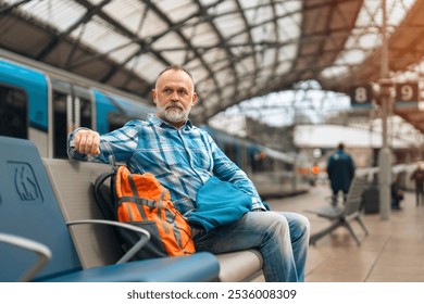 A thoughtful traveler rests on a bench at a busy railway station during morning hours - Powered by Shutterstock