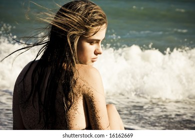 Thoughtful woman in the beach with sand in her skin.