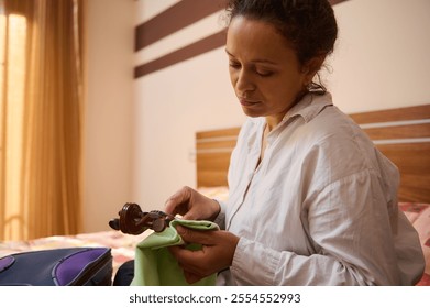 A thoughtful woman carefully cleans a wooden gavel in her bedroom. The setting is serene, with warm natural light creating a peaceful atmosphere, indicating dedication and mindfulness.