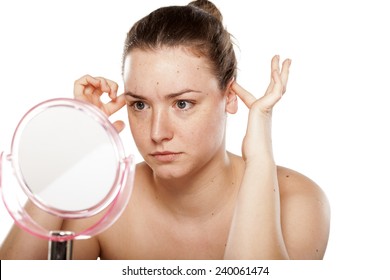 thoughtful woman looking at herself in the mirror and squeeze her ears