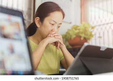 Thoughtful woman looking at laptop with hand under her chin