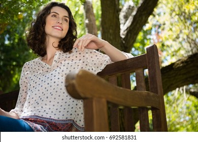 Thoughtful Woman Sitting On Park Bench On A Sunny Day