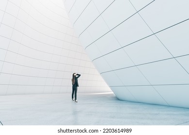 Thoughtful woman standing in abstract glass building open space interior