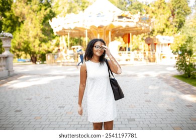 Thoughtful woman with vitiligo skin disorder carrying purse while standing at amusement park. Young woman in white dress is looking away during sunny day.  - Powered by Shutterstock