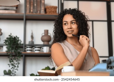 Thoughtful young African-American author with typewriter and books sitting at table in cafe - Powered by Shutterstock