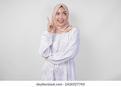 Thoughtful young Asian Muslim woman wearing white dress and hijab thinking and finding idea with happy expression, isolated on white background - Powered by Shutterstock