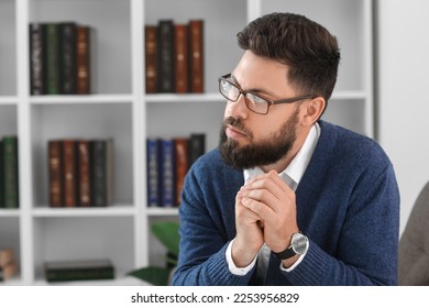 Thoughtful young bearded man in armchair at home - Shutterstock ID 2253956829