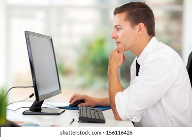 thoughtful young businessman looking at computer screen