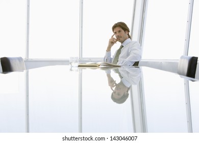 Thoughtful young businessman sitting at conference table - Powered by Shutterstock