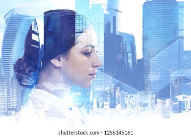 Thoughtful young businesswoman with long dark hair standing over modern cityscape background. Toned image double exposure