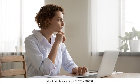 Thoughtful Young Female Doctor Thinking Of Medical Question At Workplace. Serious Doubtful Woman Professional Medic Wearing White Coat Thinking Of Problem Solution Doing Online Healthcare Research.