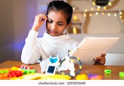 Thoughtful Young girl kid preparing DIY robot by seeing instruction manual at home - concept of making scientific experiment, Childhood learning, education and prodigy - Powered by Shutterstock