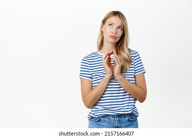 Thoughtful young girl, student thinking, steeple fingers, scheming, has an idea, plan to do smth devious, stands over white background