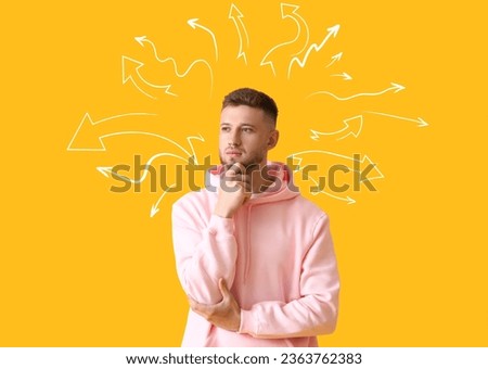 Thoughtful young guy in stylish hoodie on yellow background. Concept of choice