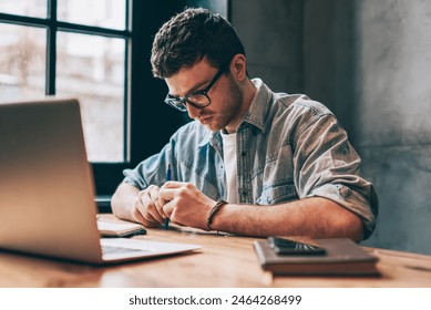 Thoughtful young male graphic designer sitting in front of laptop, casual dressed man thinking about possibility of seeking new opportunities, freelance small business owner feeling doubt indoors - Powered by Shutterstock