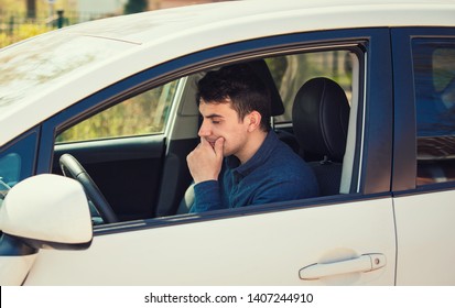 Thoughtful Young Man Driver Holding His Hand Under Chin Looking Anxious Waiting In His Car. Sad Serious Guy Stuck In Traffic Jam.