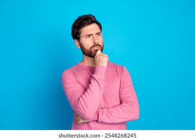 Thoughtful young man looking pensive in casual outfit against vibrant blue background - Powered by Shutterstock