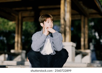 Thoughtful Young Man Relaxing Outdoors in Soft Sunlight at a Scenic Park Pavilion. - Powered by Shutterstock