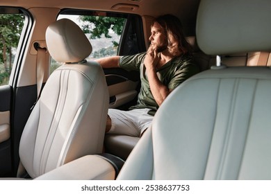 Thoughtful young man sitting in car looking out window in contemplation - Powered by Shutterstock