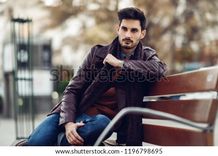 Thoughtful young man sitting on an urban bench