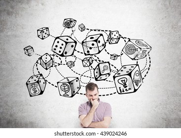 Thoughtful young man standing against concrete wall with connected dice sketch. Game and probability theory - Shutterstock ID 439024246