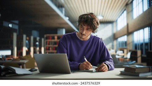 Thoughtful Young Student Preparing for Class, Doing Homework on a Laptop Computer. Freelance Journalist Working on an Article in a Public Library with Modern Simple Interior - Powered by Shutterstock