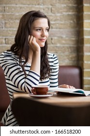 Thoughtful Young Woman With Hand On Chin Looking Away In Coffeeshop