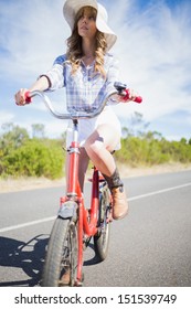 Thoughtful Young Woman Posing While Riding Bike Down A Deserted Road In Summertime