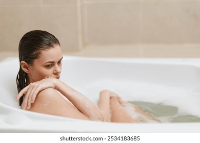 Thoughtful young woman relaxing in a bathtub surrounded by bubbles, enjoying a moment of solitude and self-care in a serene bathroom setting. - Powered by Shutterstock