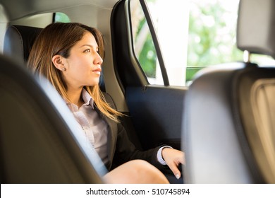 Thoughtful Young Woman In A Suit Sitting In The Backseat Of A Car And Looking Through The Window