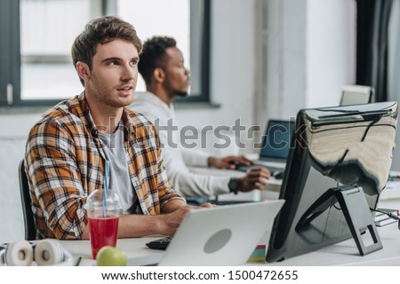 thougtful programmer looking up while working near african american colleague