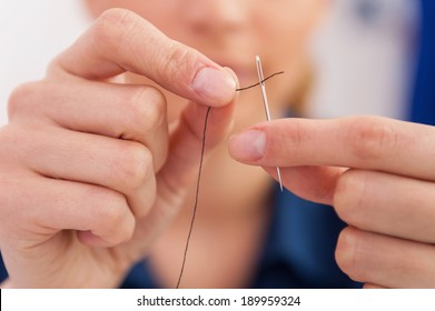 Thread Into The Needle. Close-up Of Woman Pulling Thread Into The Needle 