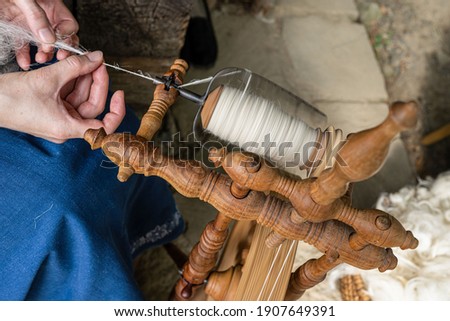 The thread maker makes the wool thread on the spinning wheel. traditional hand processing of wool by women. Traditional manual production process.