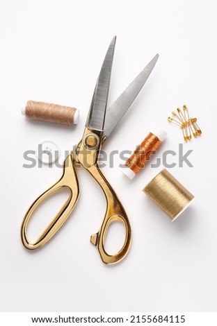 Thread spools with scissors, button and pins on white background