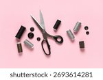 Thread spools with scissors and buttons on pink background