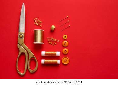 Thread Spools, Scissors, Buttons And Pins On Red Background