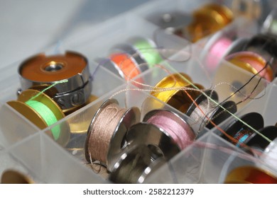 a thread storage box containing various small bobbin rolls with colorful threads, looks messy