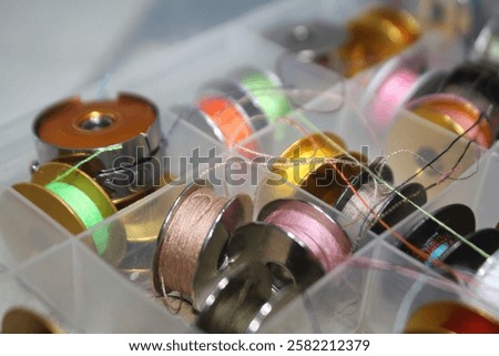 a thread storage box containing various small bobbin rolls with colorful threads, looks messy