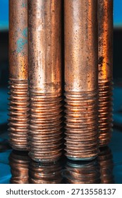 Threaded copper screws on a reflective metal surface