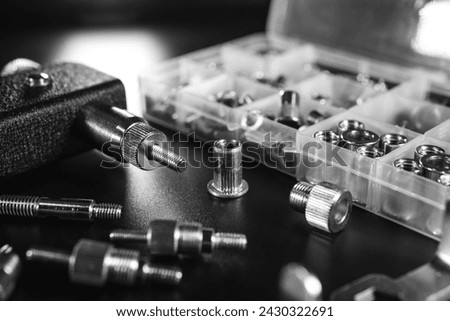 Threaded Insert Riveter Gun Kit. setting tool, nosepieces and inserts, for all types of rivets, including threaded rivet nuts, pliers. black background, selective focus. Black and white