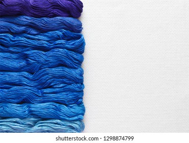 Threads of blue shades on the white canvas. - Shutterstock ID 1298874799