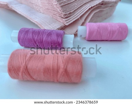 Threads and fabric in pink colors with fabric on white background. Selective focus.