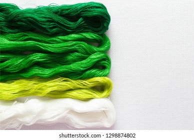 Threads of green shades on the white canvas. - Shutterstock ID 1298874802