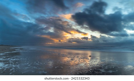 Threatening clouds and a setting sun over the North Sea along the coast of North Holland. A strong west wind, ominous clouds, and a setting sun: perfect ingredients for a landscape photo of the coast