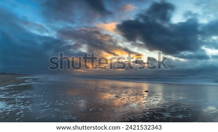 Threatening clouds and a setting sun over the North Sea along the coast of North Holland. A strong west wind, ominous clouds, and a setting sun: perfect ingredients for a landscape photo of the coast