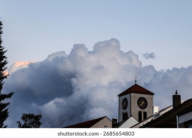 Threatening dark storm clouds with a bright pink tip over the church of St Albert in Augsburg Haunstetten